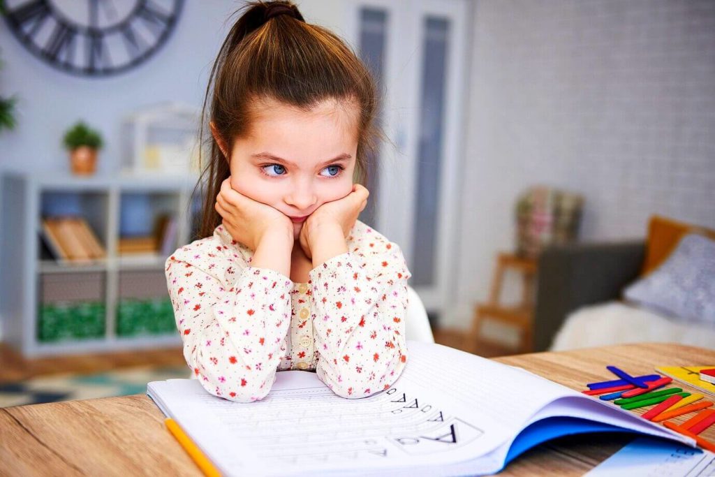 Fille déconcentrée qui fait ses devoirs