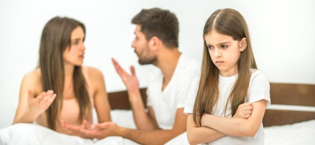 fille-triste-s-asseyant-pres-parents-qui-se-disputent