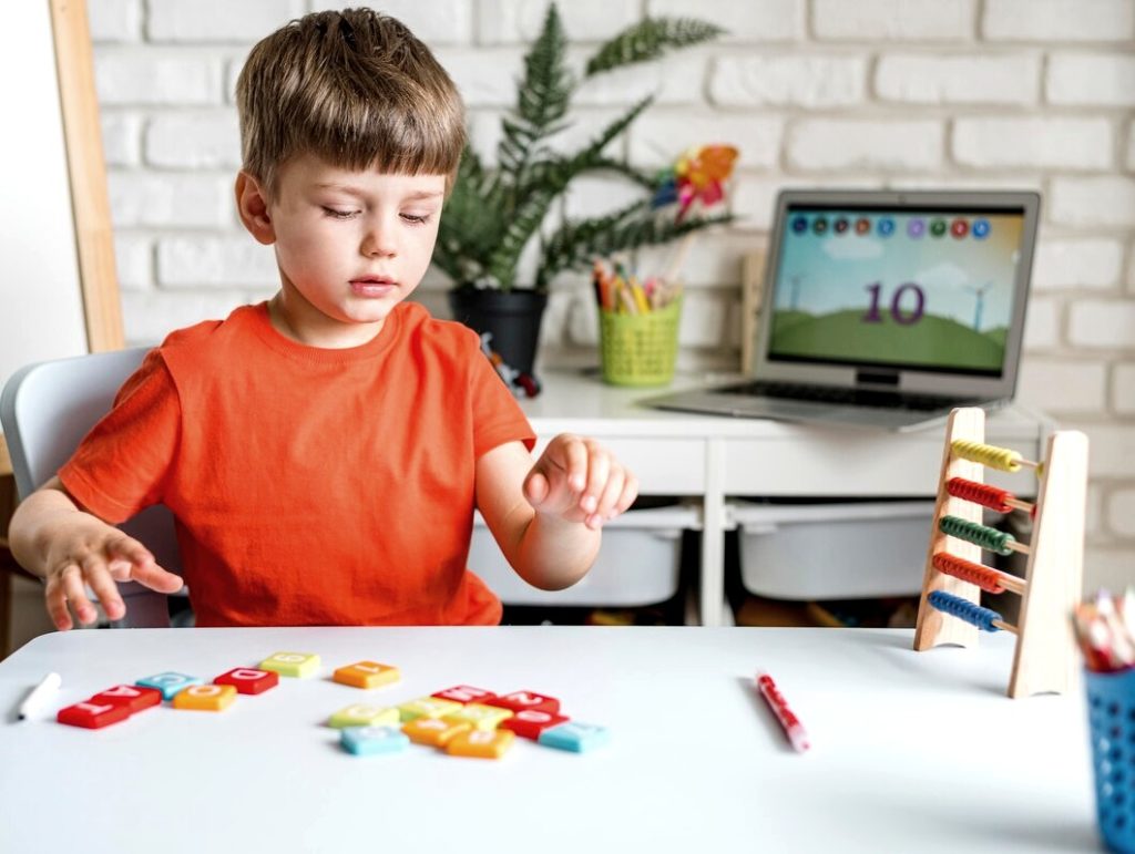 Petit garçon joue avec des lettre en bois Montessori