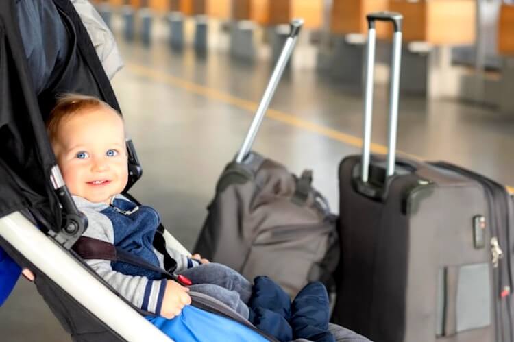 petit garçon assis dans une poussette avec bagages