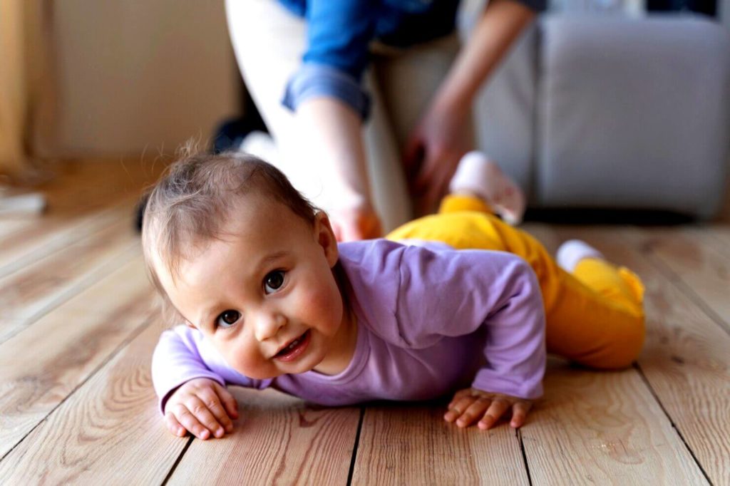 Bébé rampant avec l'aide de sa mère