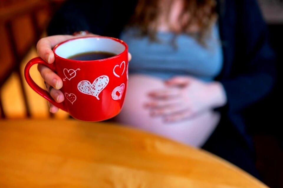 Femme enceinte tient une tasse de café