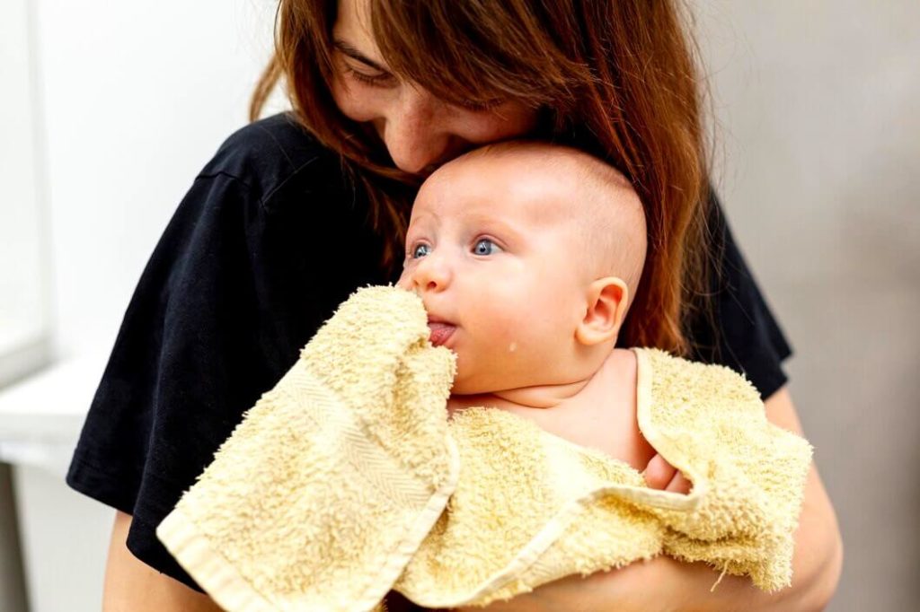 Maman enveloppe son bébé avec une serviette