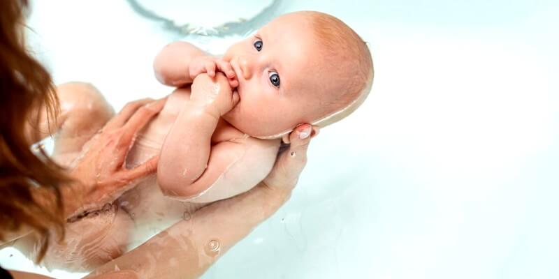 Maman lave son bébé dans une baignoire