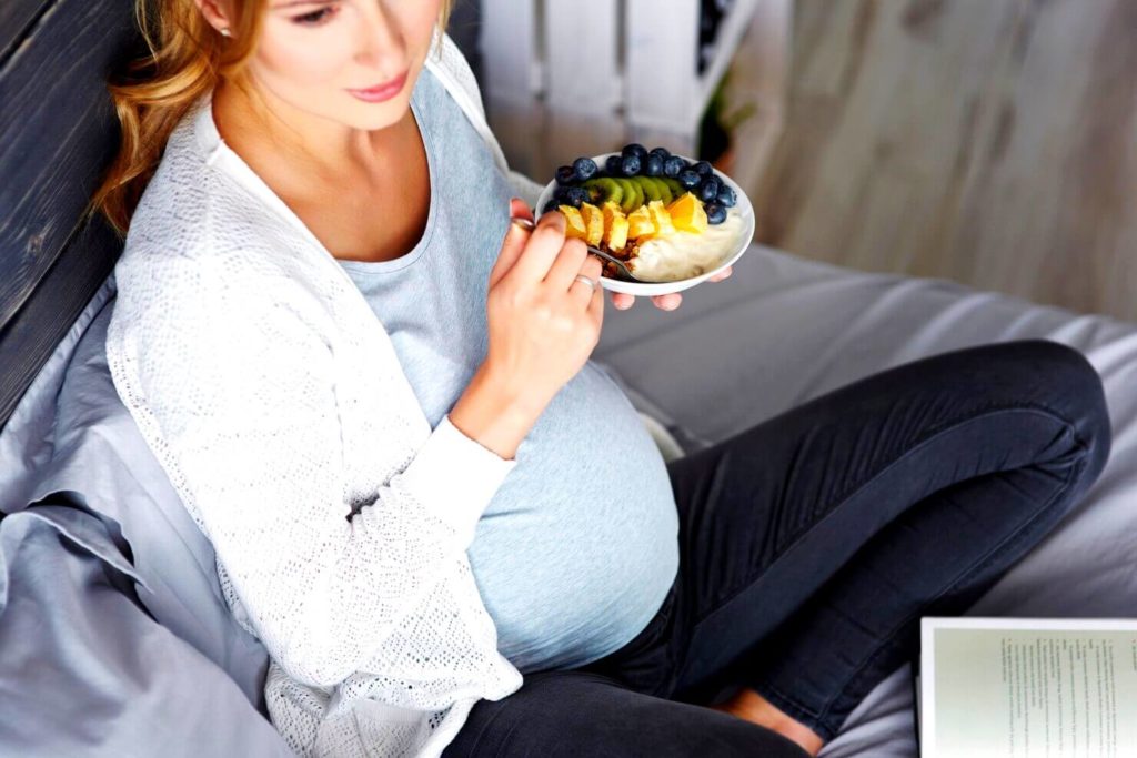 Femme enceinte qui mange une salade de fruits