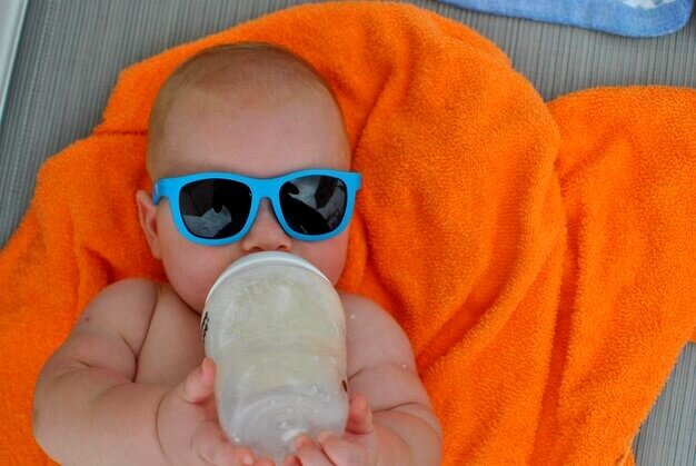 Bébé avec des lunettes de soleil boit son lait