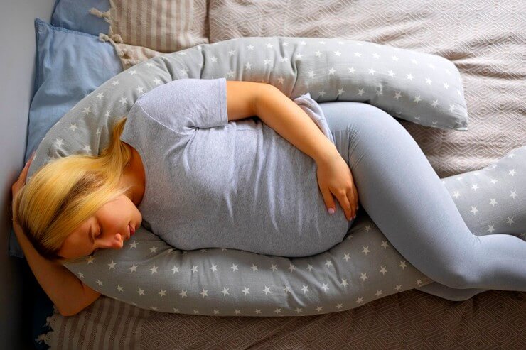 Femme enceinte dort sur un coussin de grossesse