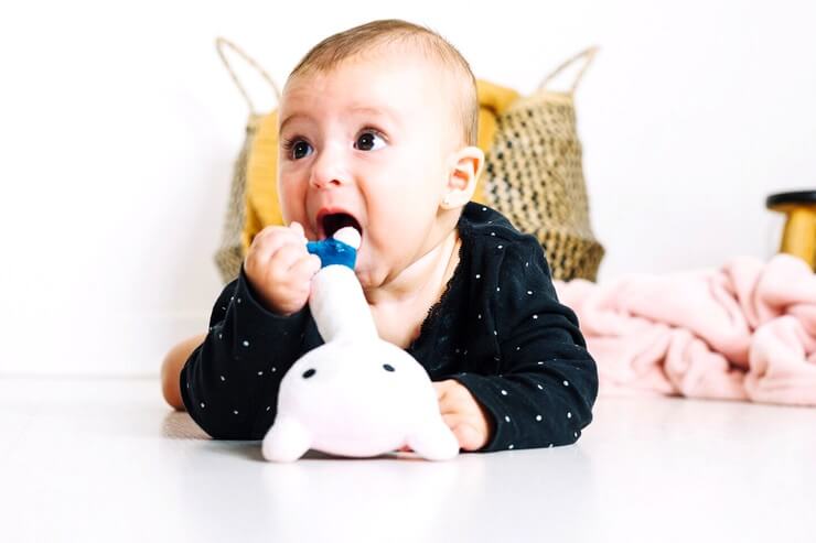Bébé avec un jouet à la bouche